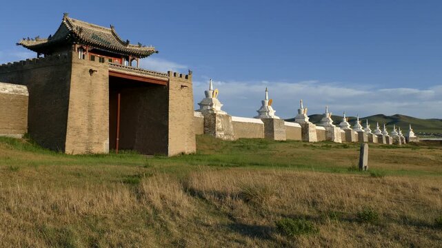 Rocky wall and stupas of the ancient Buddhist monastery of Erdene Zuu against the blue sky. Kharkhorin, Mongolia. The stupa is a sacred Buddhist structures. Sunny summer evening.