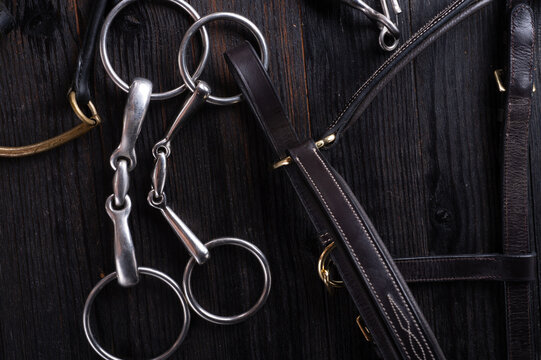 various horse bits on black wooden  table. studio shot. close up