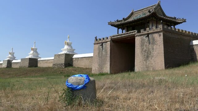 Temple in the form of a pagoda, gate and rocky wall with stupas of the ancient Buddhist monastery of Erdene Zuu against the blue sky. Kharkhorin, Mongolia. The stupa is a sacred Buddhist structure.  