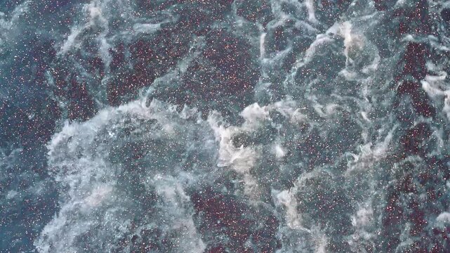 The wake behind the ship is beautiful waves in slow motion. View through sparkling particles. Slow mo, high speed camera
