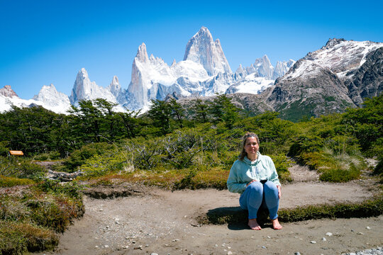Young woman sitting in front of majestic Fitz Roy mountains in Patagonia