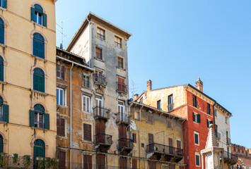 Obraz premium Historic buildings with colorful facades and balconies in Verona, Italy, showcasing architectural details against a clear blue sky