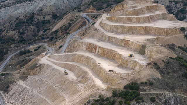 An aerial drone photo of the terraced limestone quarry on the mountainside and the winding access road.