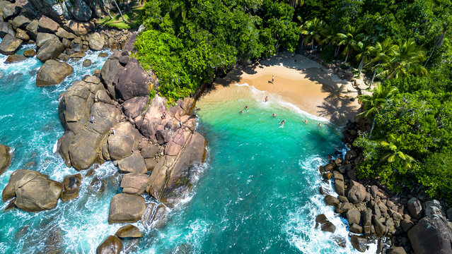 Aerial drone view of Portugues Beach in Ubatuba, Brazil. Hidden tropical cove with crystal clear turquoise water, white sand and lush rainforest coastline in Sao Paulo state.