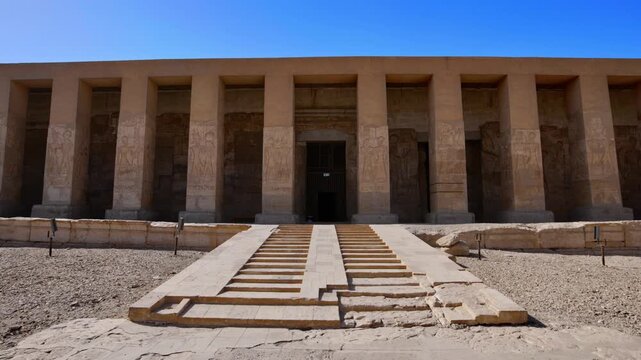 Abydos Temple of Seti I facade with grand stairway and colonnade in Egyptian desert. One of Egypt's most sacred ancient sites under vivid blue sky. Egypt.