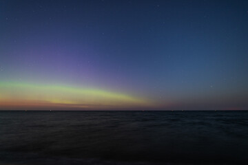 Fototapeta premium Aurora borealis dances over the Baltic Sea in Poland under a starry sky