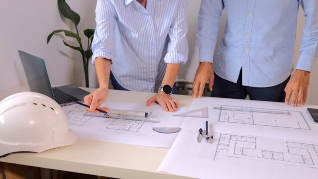 Architects and engineers collaborating on a new building design, reviewing blueprints, discussing construction plans, and developing a housing project