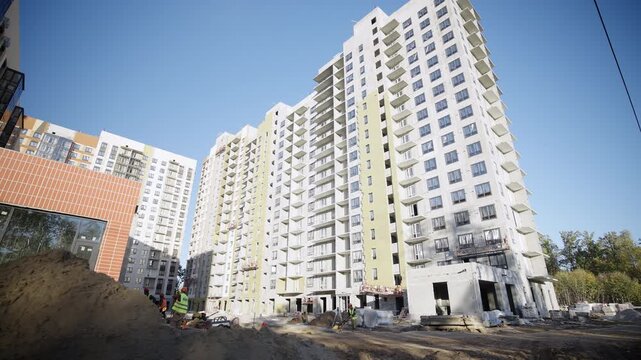 Dug trench in yard of modern multistory apartment building in spring town. Constructing innovative dwelling complex in urban block against sky
