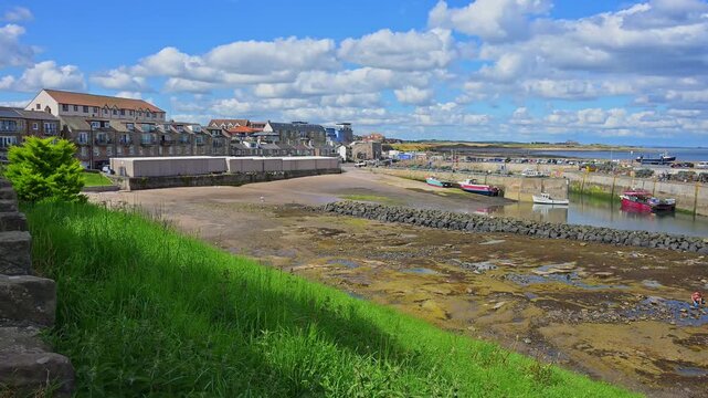 Ein kleiner Hafen mit Booten bei ruhigem Wetter unter einem blauen Himmel mit einigen Wolken, Seahouses, Northumberland, England, Gro&szlig;britannien
