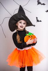 Fototapeta premium Cute girl in witch costume with pumpkin.