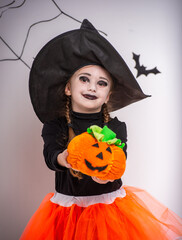 Fototapeta premium Girl in witch costume showing pumpkin.
