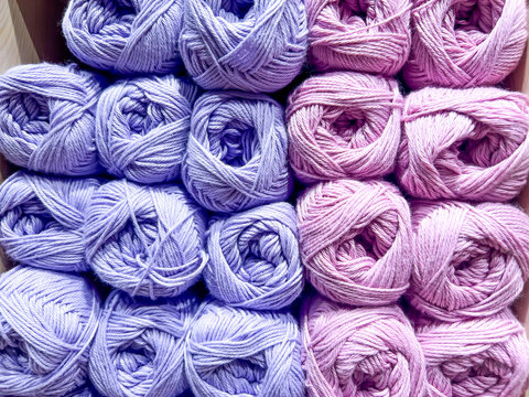Balls of mauve and pink wool neatly arranged and on sale in a haberdashery shop
