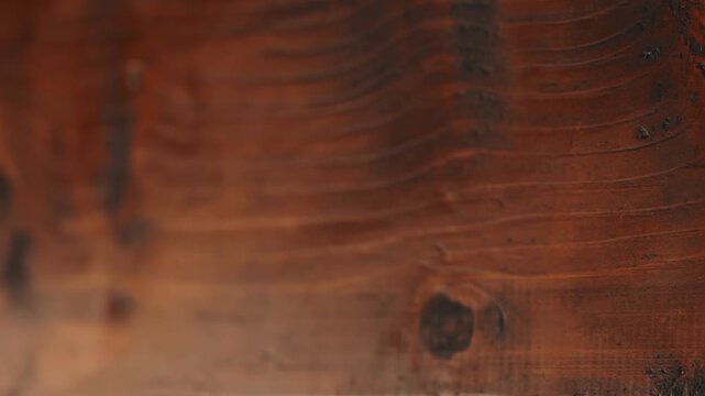 Macro slow motion shot of wood plank. Camera moves right to left showing beautiful wood grain, knots, and wavy lines. Close-up with sharp right side and soft blurred left. Perfect background.