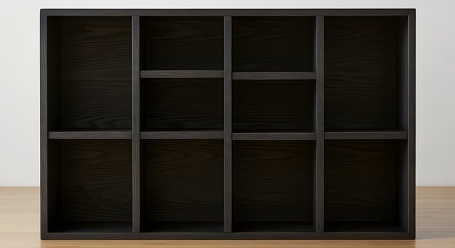 Minimalist black wooden cubby shelf unit on light wood floor against white wall background.