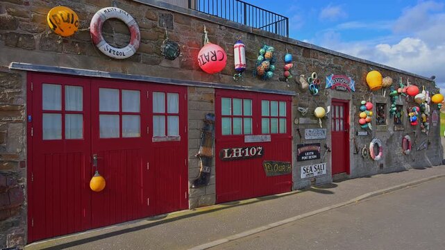 Eine Wand mit roten T&uuml;ren, dekoriert mit bunten Bojen und Seemotiven, Dunbar, East Lothian, Schottland, Vereinigtes K&ouml;nigreich, Gro&szlig;britannien