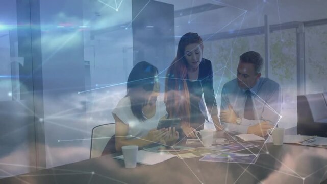 Team tapping tablet arranging layouts in business meeting cloud network marking designs for review