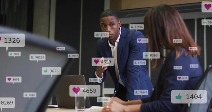 Leaning man in navy suit pointing at laptop on meeting table while woman taking notes, overlays
