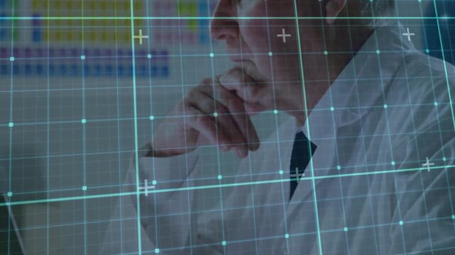 Senior male medic typing, pausing, resting chin while analyzing heatmap with teal HUD on screen