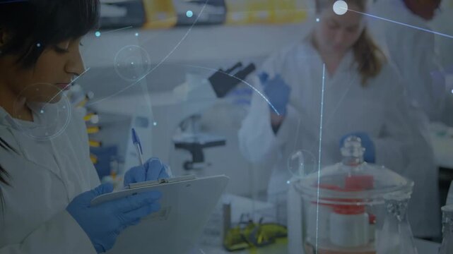 Camera panning sparking sci overlay while woman scientist noting clipboard and pipetting tubes lab