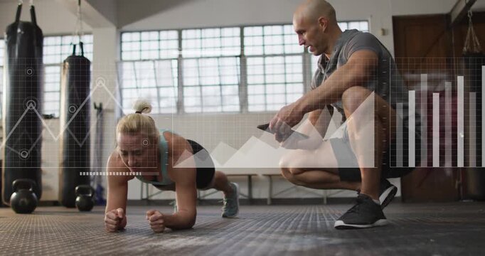 Female client holding plank on rubber floor and male trainer tapping tablet starting fitness charts