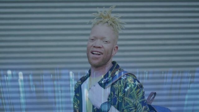 Vertical video: Smiling man in leaf shirt tugging blue pack while camera rolling at shutter, glitch