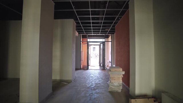 Motion along unfinished office building lobby to entrance at construction site. Releasing modern residential house project in urban block