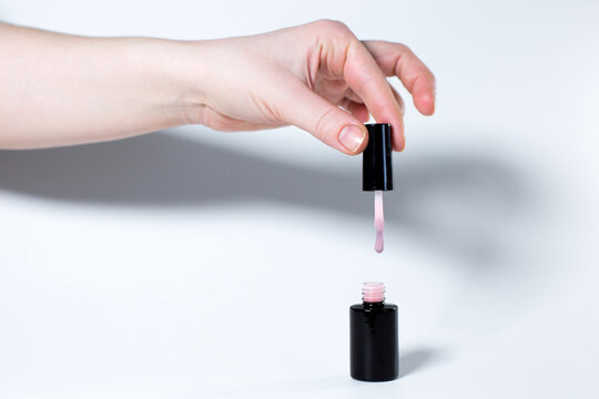 Black nail polish bottle with hand isolated on white background, copy space template.