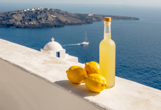 Bottiglia di limoncello con limoni e vista sul mare