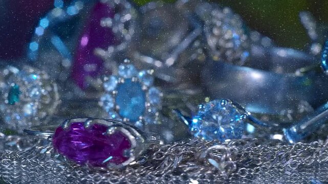 Beautiful shiny, sparkling golden jewelry on a glass surface with bright flares is rotation. View through sparkling particles. Macro. Closeup. Shallow depth of field