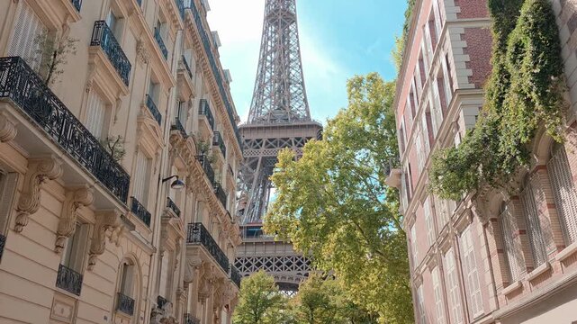 Iconic Eiffel Tower. Upward, handheld panning motion through the grand buildings of Paris, France.