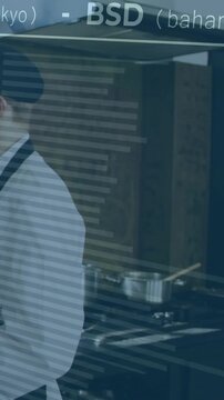 Vertical video: Chef shifting at stove as scrolling currency overlay crosses glass, linking finance