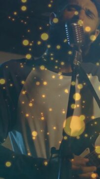 Band lead singer-guitarist leaning into mic, camera moving closer, singing with gold bokeh for mood