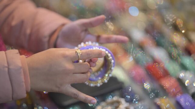 Woman buying bangles at fair market, Indian mela bangle shopping close up, Traditional bangles selection in local market, Female hands choosing colorful bangles stock video.