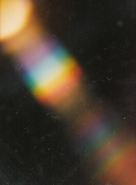 Rainbow light leak prism effect on dark vintage film grain texture