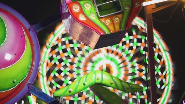 Colorful amusement ride at night with bright lights, Spinning fair ride with vibrant neon patterns, Carnival ride close up with motion and lights, Funfair attraction glowing in night scene stock video