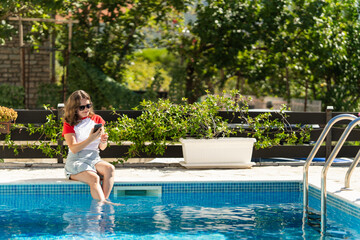 Naklejka premium Woman with smartphone near a swimming pool