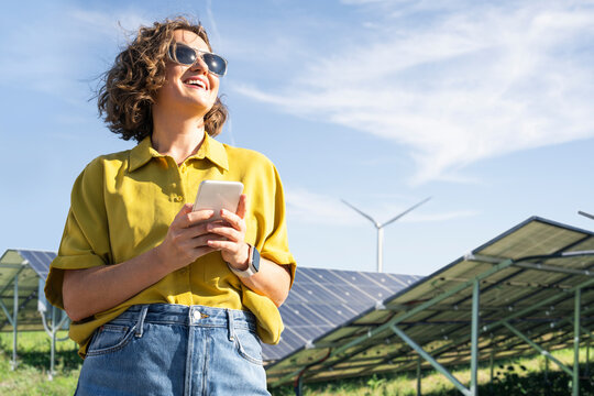 Woman with smartphone at clean energy site solar and wind power farm