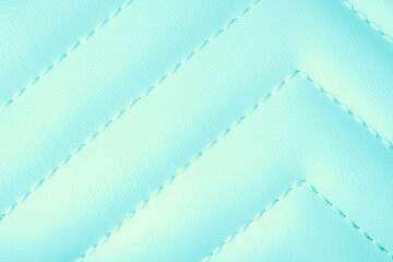 Fototapeta premium Detailed view of vibrant light blue quilted leather texture with intricate zigzag stitching surface
