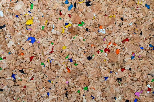 Natural brown cork texture with vibrant multicolored fragments. A sustainable and eco-friendly background ideal for modern office, education, or creative design projects. Colorful recycled cork board