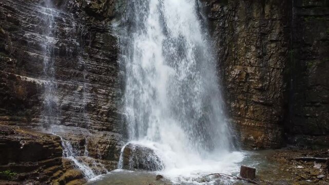 Waterfall falling from the high cliff in spring overcast day