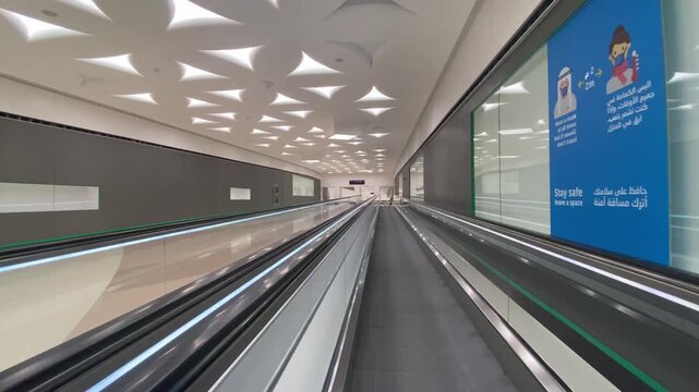 DOHA, QATAR - MARCH 10,  2024: Point of view shot walking on moving walkway (travelator) inside modern transport hub with geometric ceiling design and strong leading lines. Editorial use only.