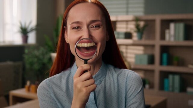 Happy Caucasian business woman holding magnifying glass face smiling indoor office funny grimacing curious female manager investigating searching research businesswoman employer girl zoom eye analysis