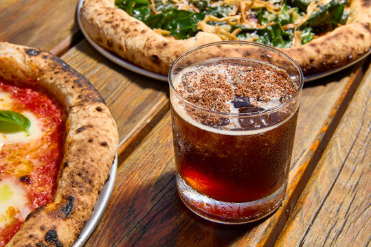 outdoor sunny setting with two pizzas and cocktail