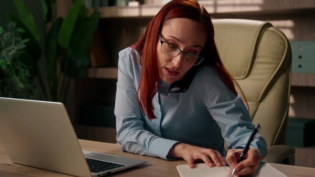 Busy Caucasian business woman multitasking laptop mobile phone working indoor office stressed manager overworked businesswoman female deadline online work writing notebook talk call problem workplace