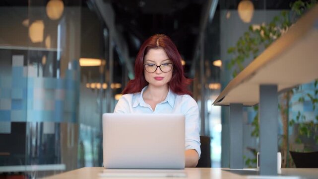 Young woman working on laptop with a satisfied expression