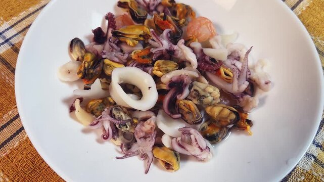 Mix of boiled seafoods in white bowl on checkered napkin