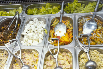 Assorted fresh salads and warm cooked dishes displayed on a self service buffet counter