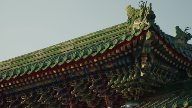 Ornate Chinese temple roof closeup showing intricate glazed tiles, dragon ornaments, layered eaves and carved brackets under soft morning light cinematic drone pan captures symmetry, texture