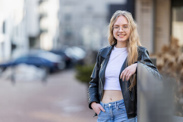 Young Woman Leaning on Railing in Leather Jacket Urban Casual Portrait With Glasses and Smile © Mindaugas Dulinskas