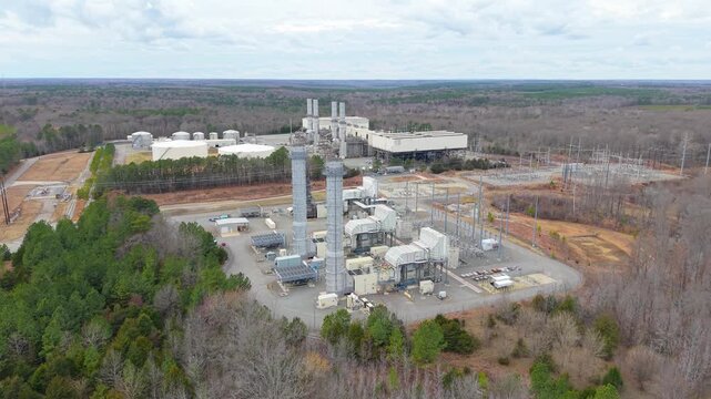 Industrial oil-fired power station, aerial video featuring generation units, electrical substations, and surrounding infrastructure at the edge of a forest.